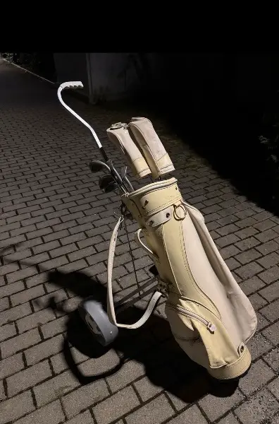 Golftasche mit fünf Schlägern und klappbare Wägelchen.