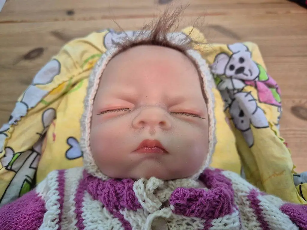 realistische Babypuppe im Tragekorb